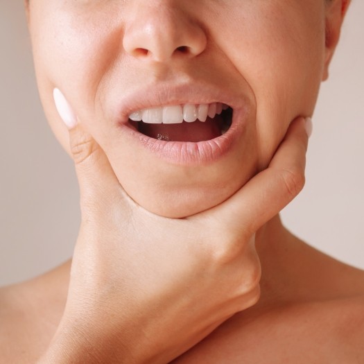 Close up of person holding their jaw in pain