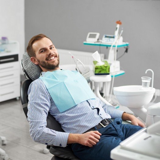 Man with short beard leaning back in dental chair
