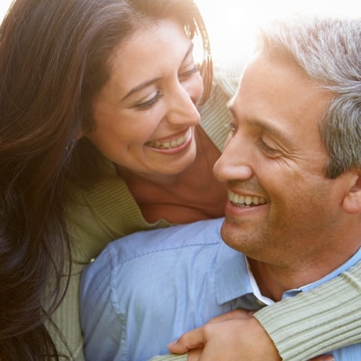 Man and woman smiling at each other after restorative dentistry in San Antonio