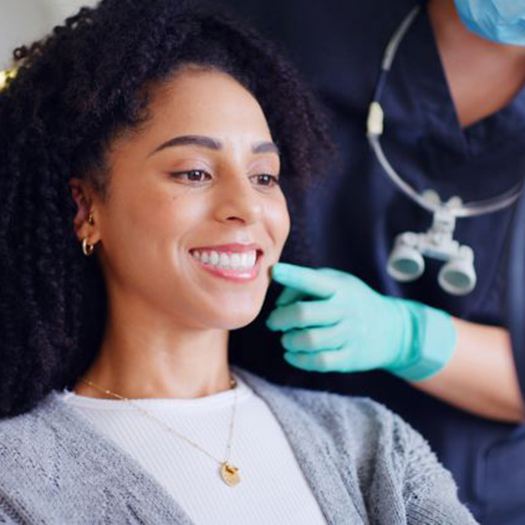 Happy dental patient looking at her smile in hand mirror