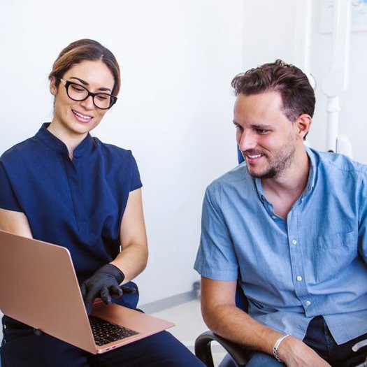 Dental team member using computer to share information with patient 