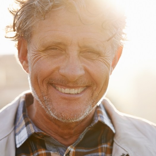 Older man smiling outdoors with dental implants in San Antonio