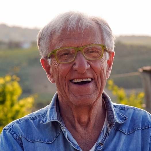 Senior man in denim shirt grinning outdoors