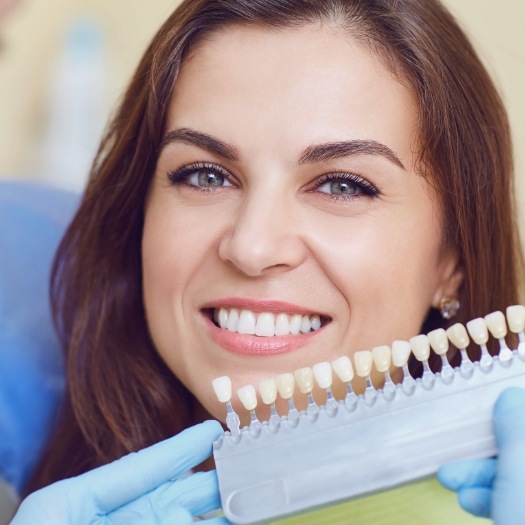 Cosmetic dentist holding a shade guide to a smiling patient