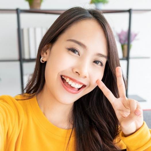 Young woman smiling and giving the peace sign