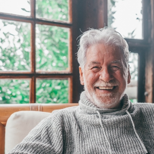 Man in gray sweater smiling after tooth extractions in San Antonio