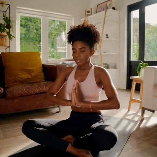 Woman meditating on a yoga mat in her living room