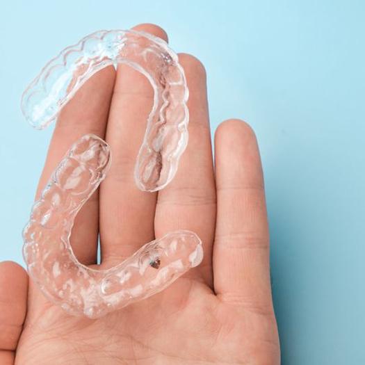 Two clear aligners resting on person’s hand