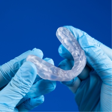 Two gloved hands holding an oral appliance
