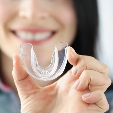 Smiling woman holding clear oral appliance