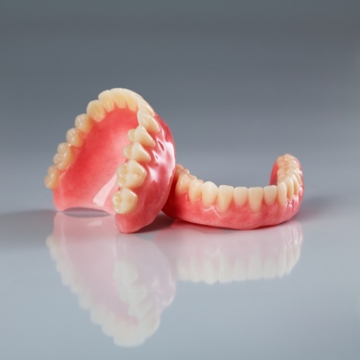 Set of full dentures on gray background