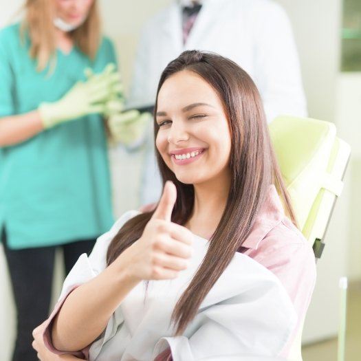Woman winking and giving thumbs up in dental chair
