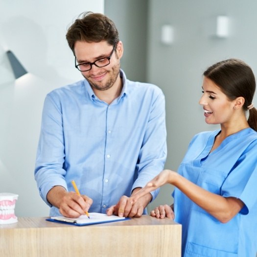 Dental team member showing a patient where to sign on clipboard