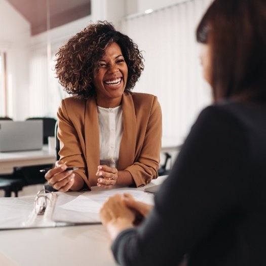 Woman laughing with someone sitting across desk