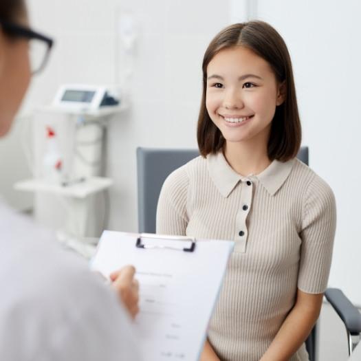 Woman smiling as her dentist writes on clipboard