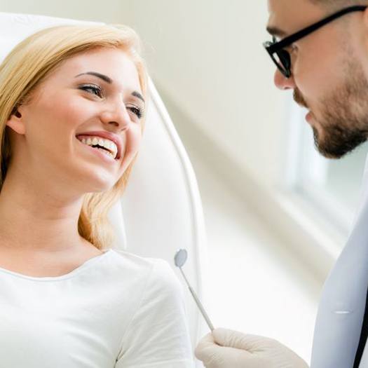 Smiling patient talking with her dentist