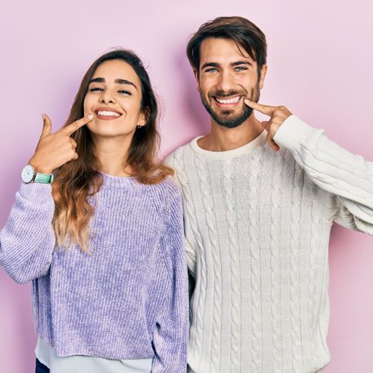 Happy couple pointing at their smiles