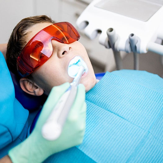 Dental team member using curing light in patient’s mouth