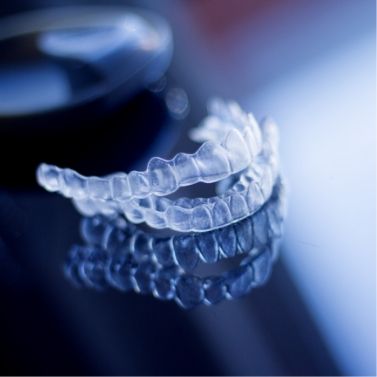 Two Invisalign clear aligners on dark gray background
