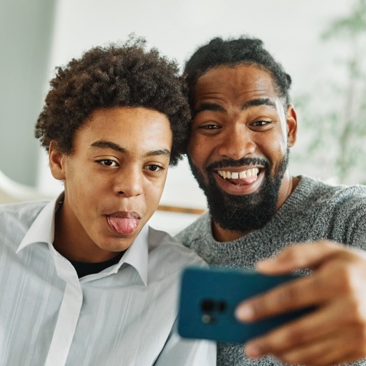 Father and teenage son taking selfie together