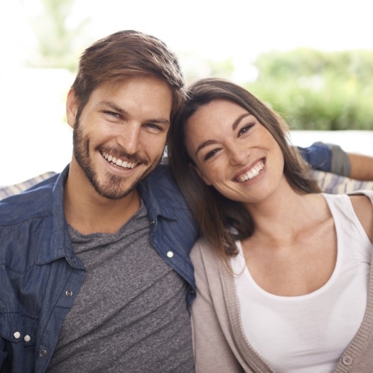 Young man with his arm across back of couch behind young woman