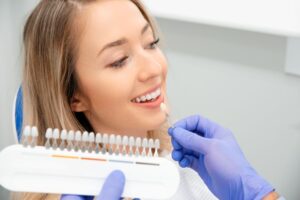 Dentist holding shade guide next to patient's teeth