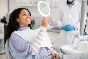 Happy dental patient looking at her smile in mirror