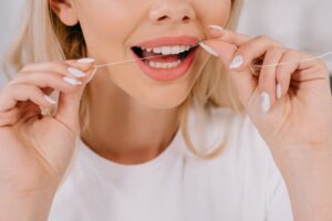 Close-up of woman’s mouth as she flosses between her teeth 